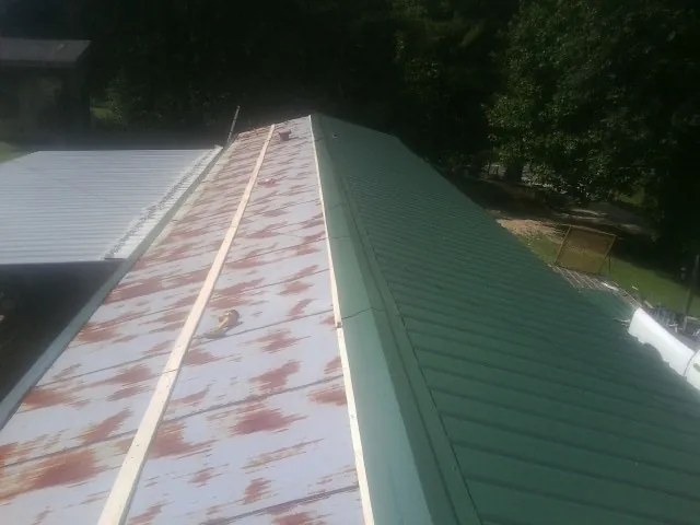 Old rusted panels beside newly installed green metal roofing — Wind Damage Roof Repair by Roofing Brothers in Lewiston Woodville