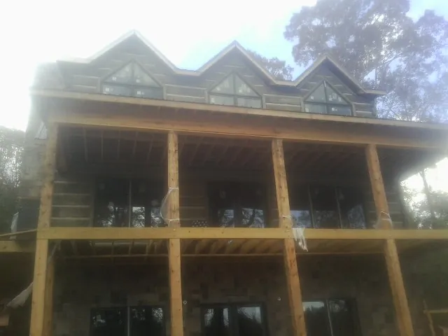 Dormers and porch framing on a large log home under construction — Roof Coating work by our crew in Lewiston Woodville