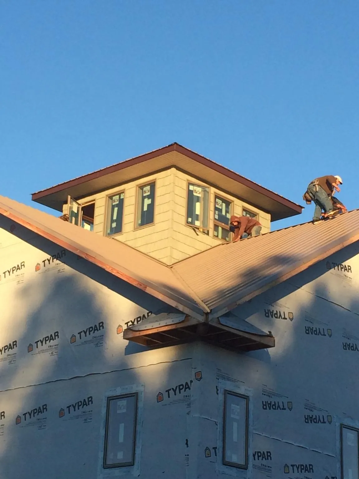 Roofers working around a rooftop cupola on a new metal roof at sunset — Roof Waterproofing in Lewiston Woodville by Roofing Brothers